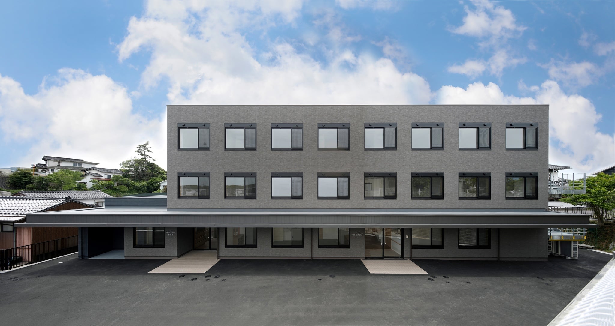 モダンな2階建て介護施設の外観。グレー基調で整理された窓配置が特徴的。